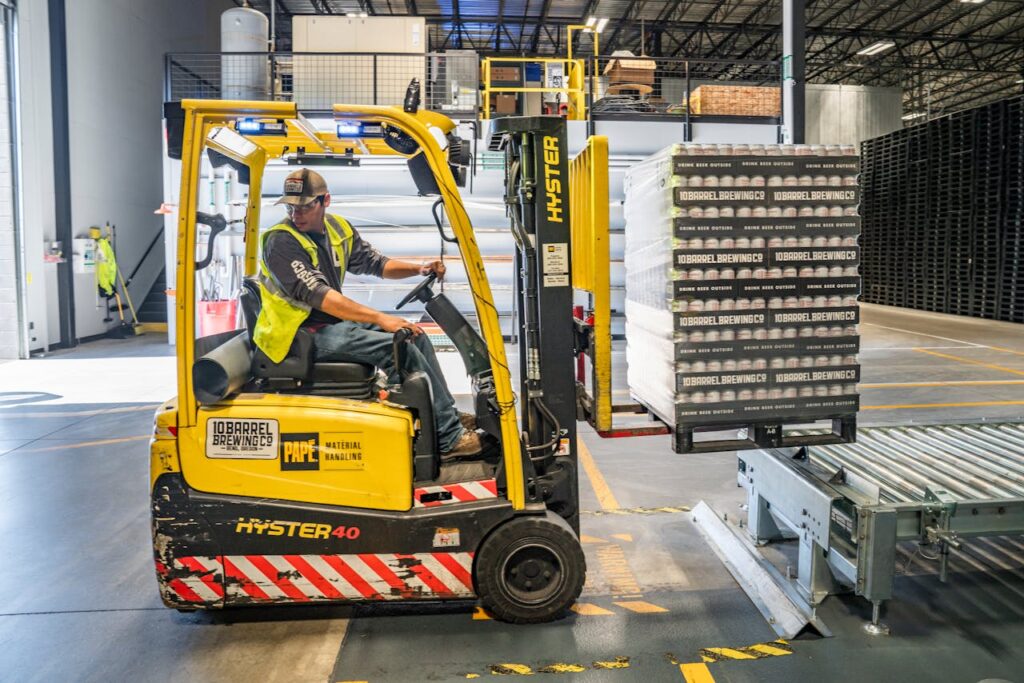 Mastering the First Impression: Your intriguing post title goes here A warehouse worker maneuvers a forklift to transport crates for brewing company storage.