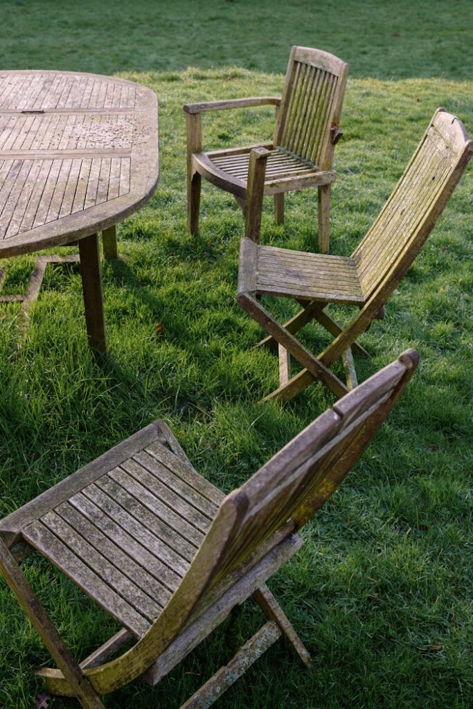 Crafting Captivating Headlines: Your awesome post title goes here A set of weathered wooden chairs and table on a grassy lawn, conveying rustic charm.